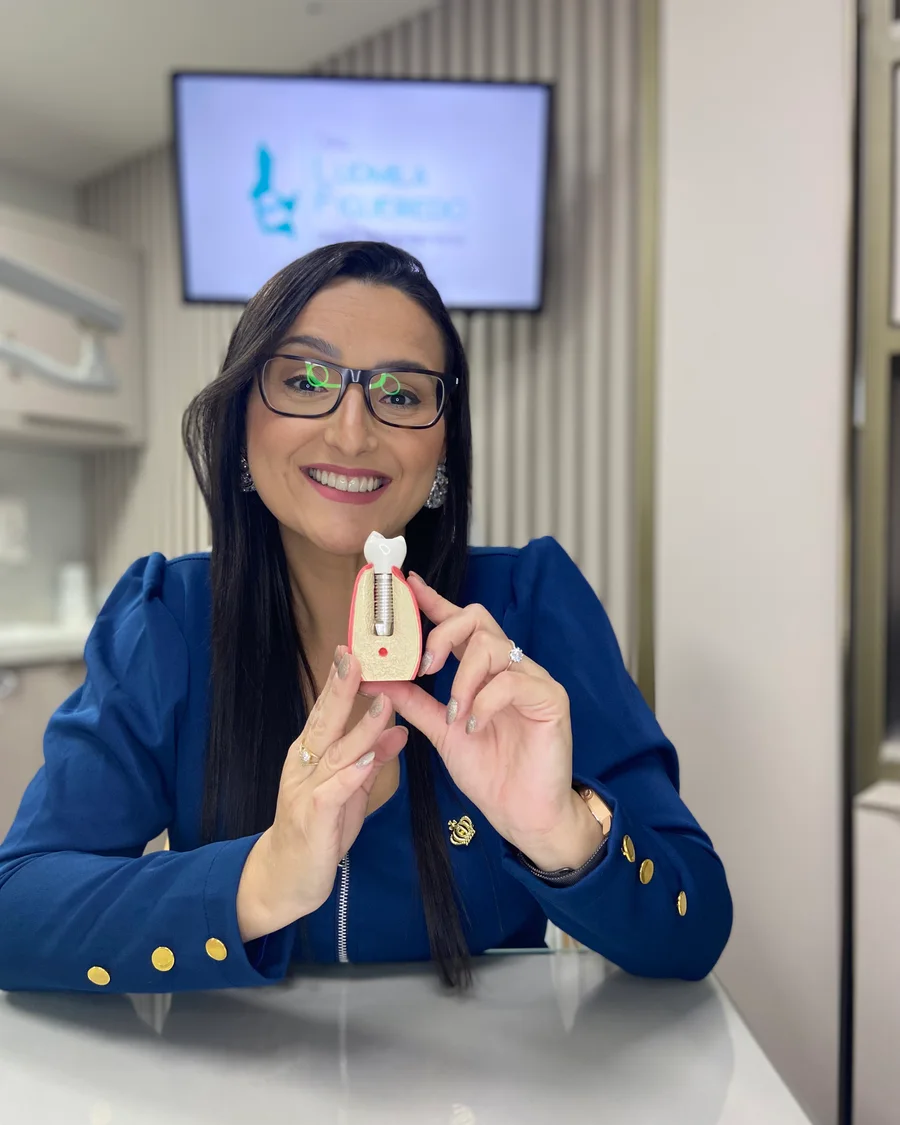 Dra. Ludmila Figueiredo apresentando um implante dentário em seu consultório